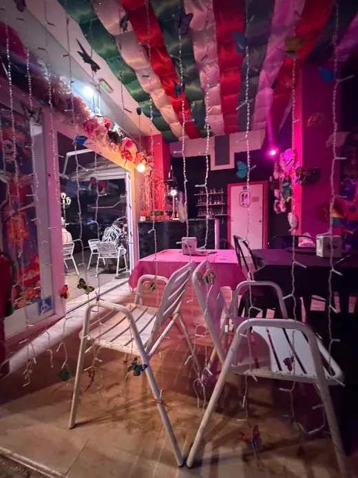 Comedor de La Eskinita de noche, con luces cálidas y decoración de Día de Muertos
